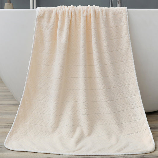 Beige textured bath towel draped over a white bathtub.