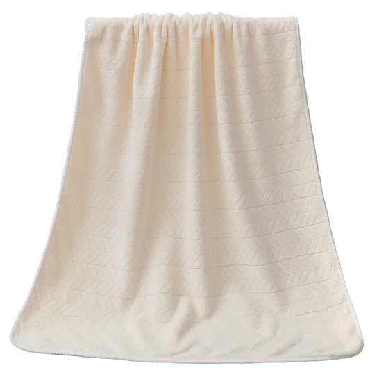 Beige textured bath towel draped over a white bathtub.
