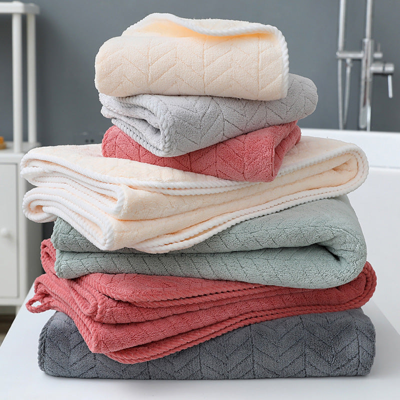 Stack of folded towels in various colors on a white surface with a neutral background