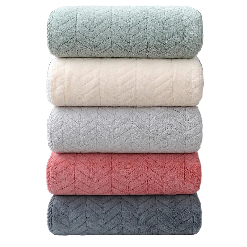 Stack of five textured towels in green, white, gray, pink, and blue on a white surface.