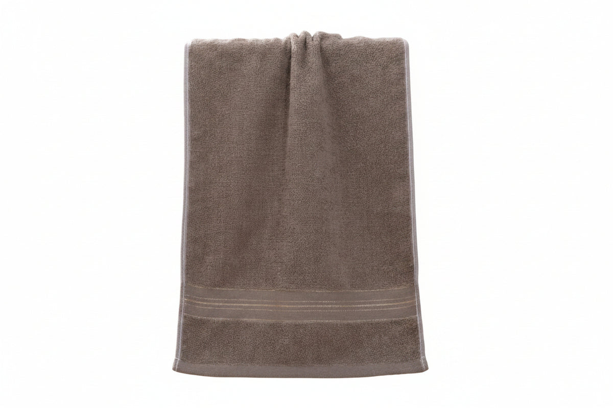 A taupe brown cotton hand towel with a decorative striped border, draped over a light wood cane-back chair.