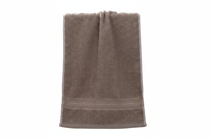 A taupe brown cotton hand towel with a decorative striped border, draped over a light wood cane-back chair.
