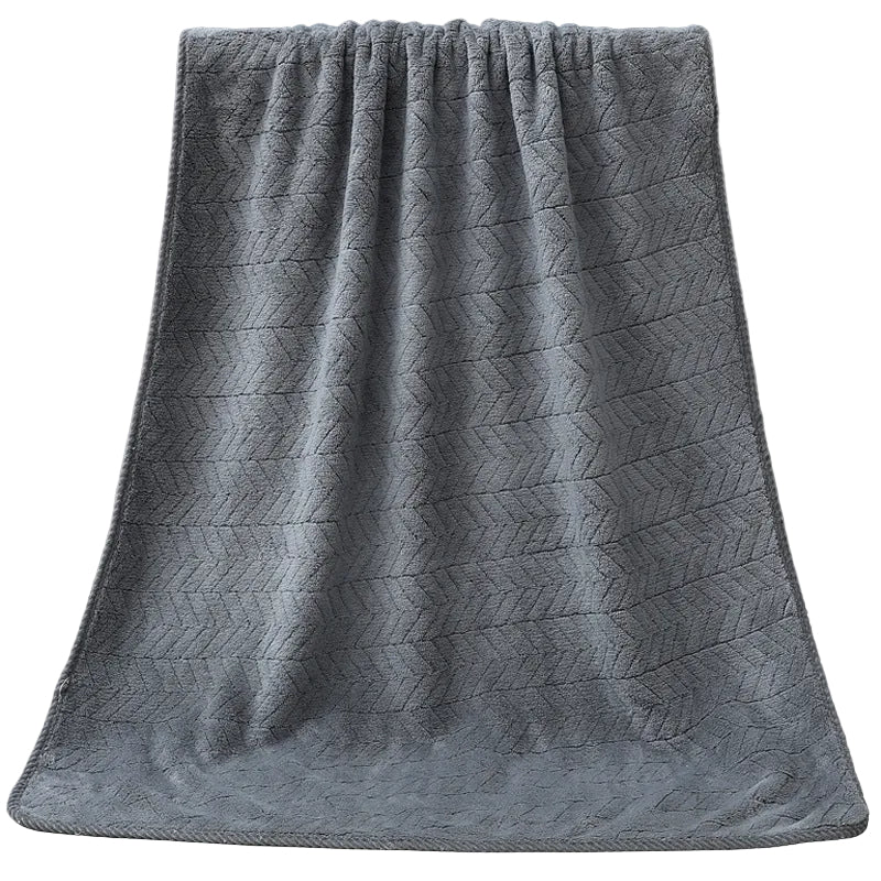 Gray textured towel draped over a white bathtub.