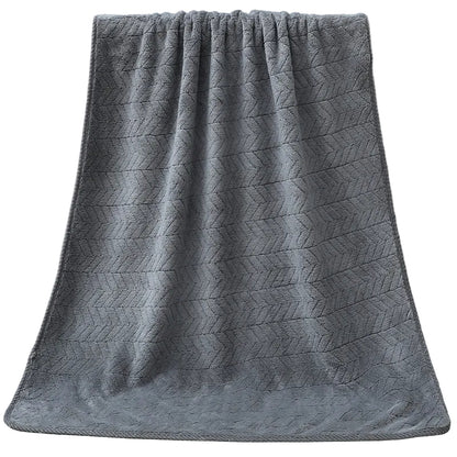 Gray textured towel draped over a white bathtub.