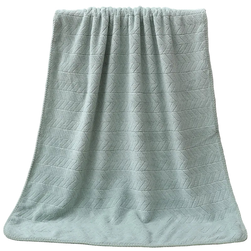 Green textured towel draped over a white bathtub.