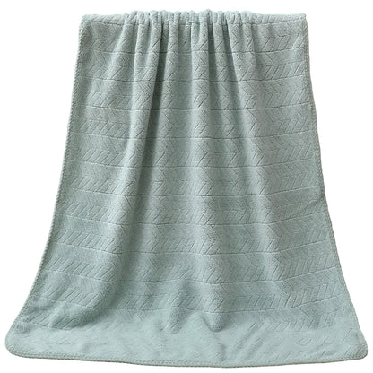 Green textured towel draped over a white bathtub.