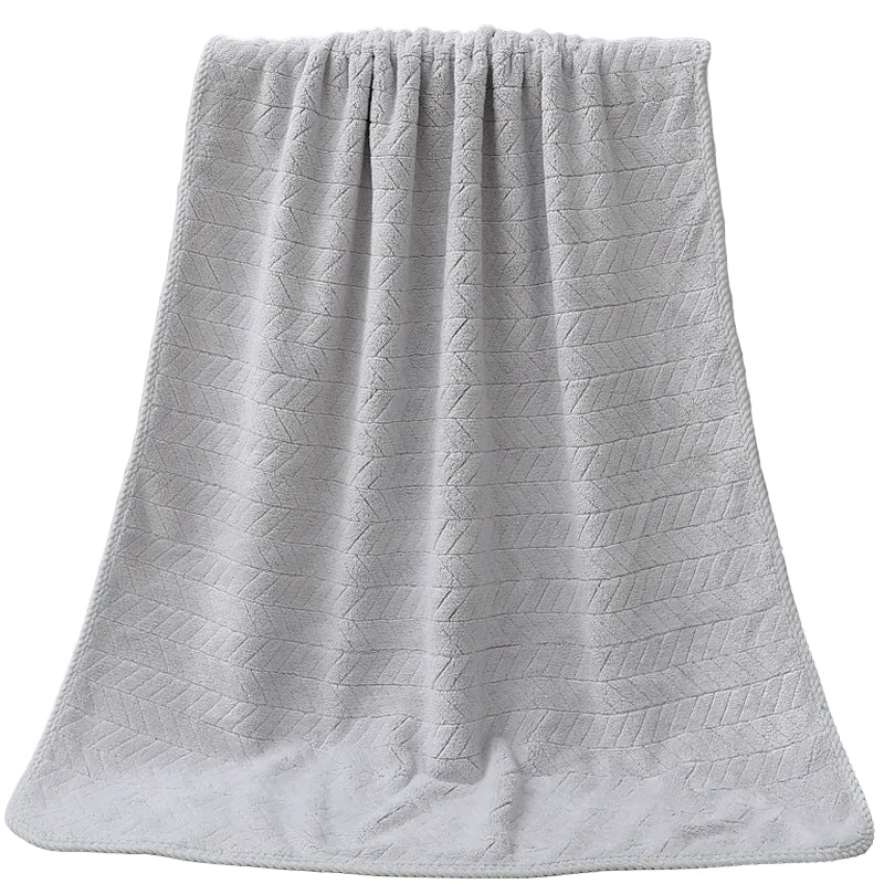 Gray textured bath towel draped over a white bathtub.