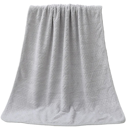 Gray textured bath towel draped over a white bathtub.