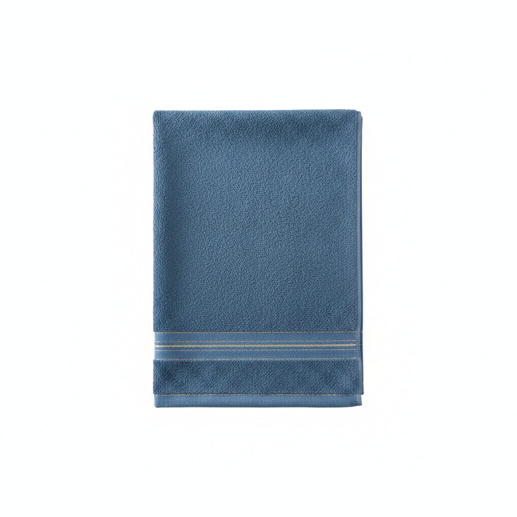 A blue cotton towel with a decorative gold stripe border draped over the back of a wooden cane chair.