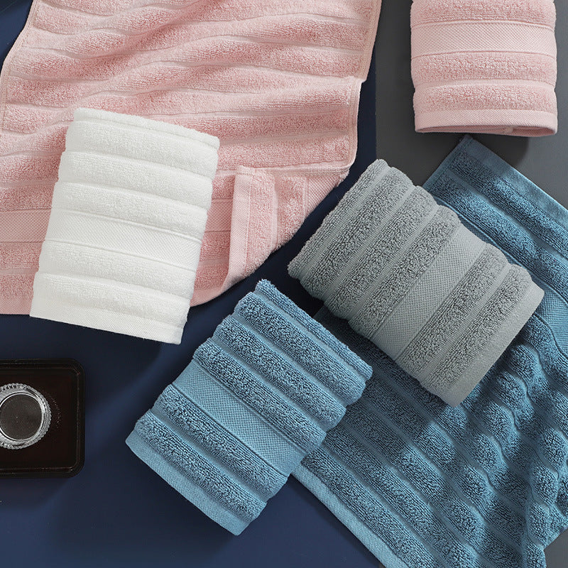 Set of folded towels in pink, white, gray, and blue on a dark surface.
