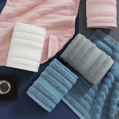 Set of folded towels in pink, white, gray, and blue on a dark surface.