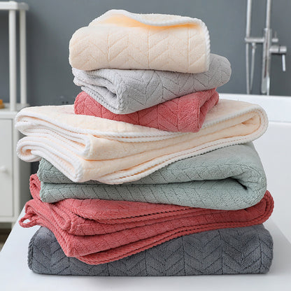 Stack of folded towels in various colors on a white surface with a neutral background